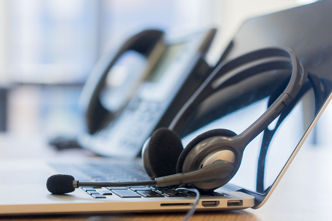 Headset auf einer Laptoptastatur neben einem Tischtelefon: klassische Kundenbetreuung im Mittelstand